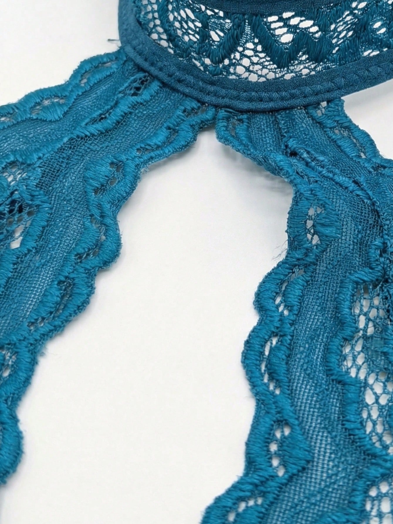 Teal blue floral lace crotchless teddy bodysuit lingerie with scallop trim, halter neckline, crossback straps, sheer unlined design, triangle cups, and thong-style low-rise bottom.