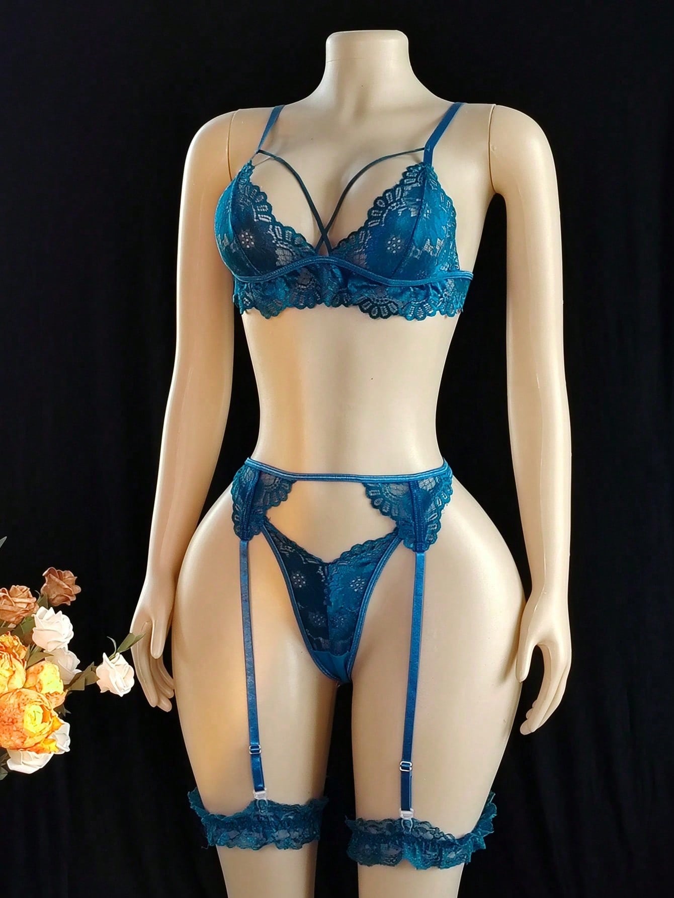 Women’s sexy lingerie set featuring a wireless bralette with adjustable spaghetti straps, matching G-string thong, garter belt, and one pair of leg rings. Plain pattern with contrast lace and criss-cross detail in a romantic style.