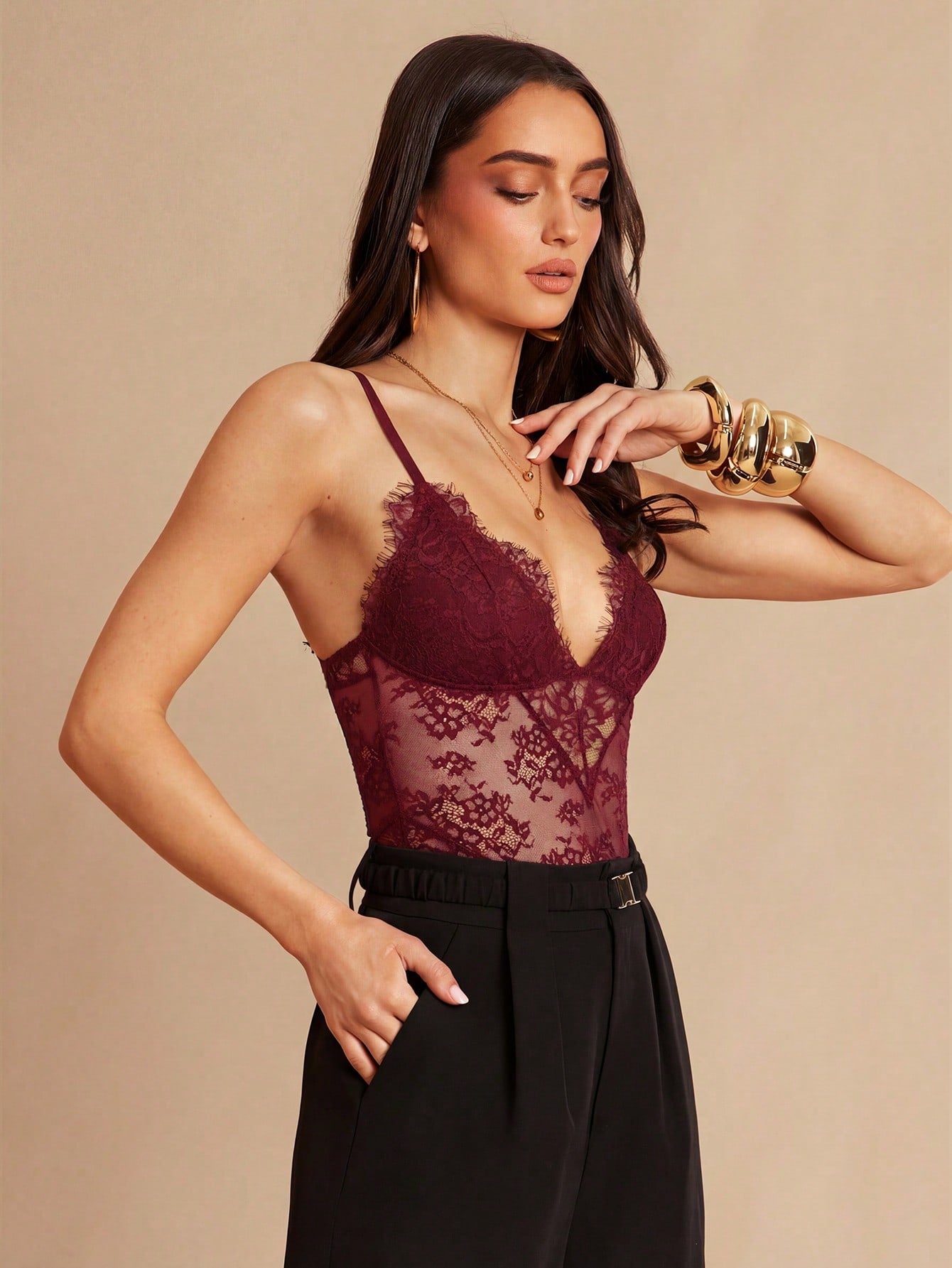 Women's black bodysuit with lace trim, sheer details, backless design, and spaghetti straps in a slim-fit cami style.