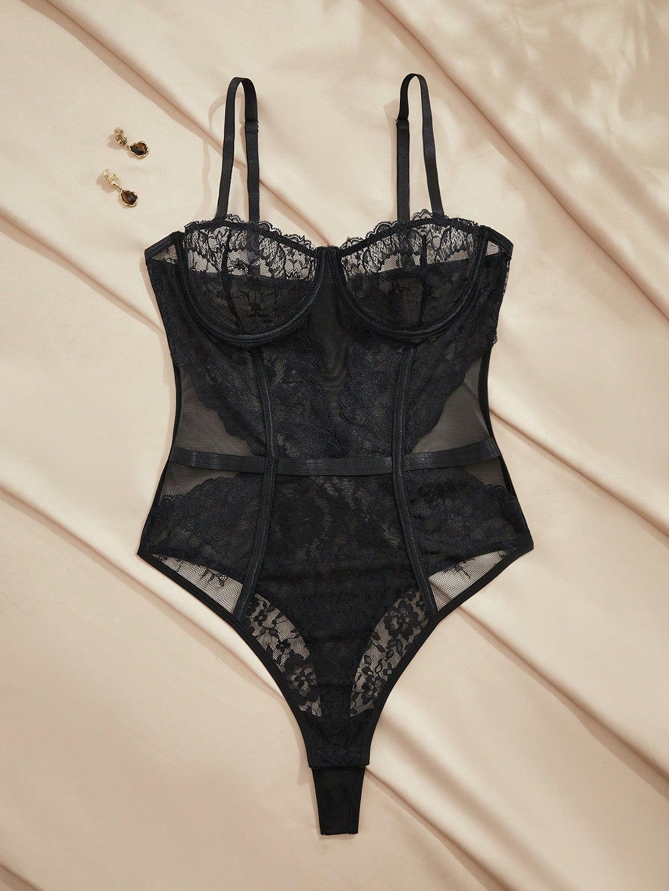 Black sleeveless women's teddy bodysuit lingerie in lace mesh with a semi-sheer finish, plant pattern detail, backless design, brief-style bottom, and underwire support.