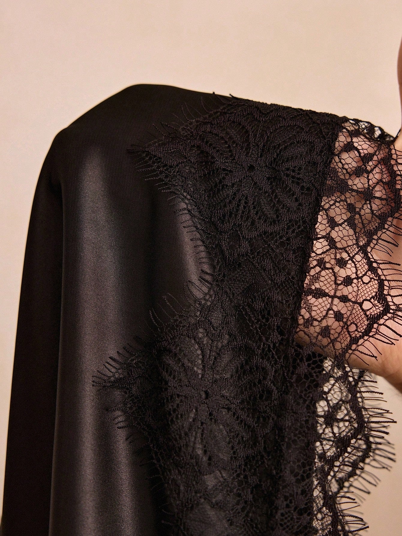 Black satin mini nightgown with contrast lace patchwork, deep V neckline, sleeveless design, and semi-sheer elegant finish