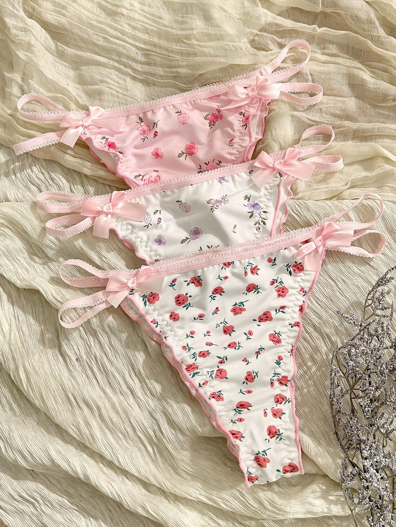 Three-piece set of pink women's low-rise brief panties with floral styling, bow waist accents, contrast lace, contrast binding, and cut-out details.