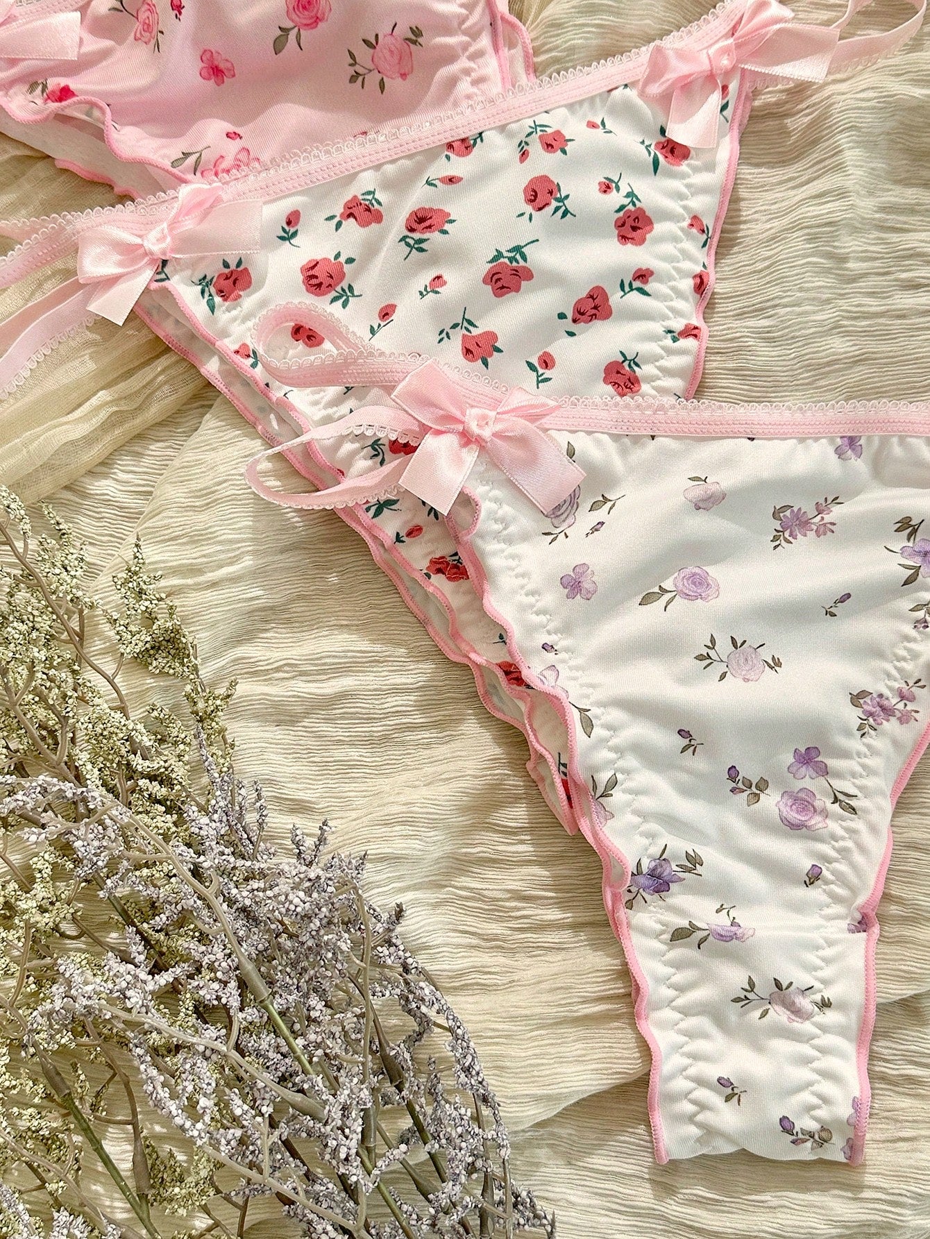 Three-piece set of pink women's low-rise brief panties with floral styling, bow waist accents, contrast lace, contrast binding, and cut-out details.