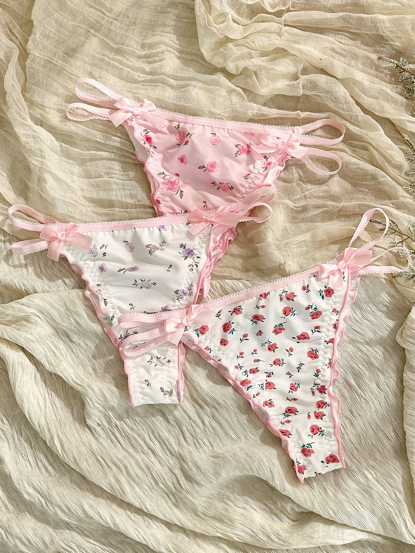 Three-piece set of pink women's low-rise brief panties with floral styling, bow waist accents, contrast lace, contrast binding, and cut-out details.