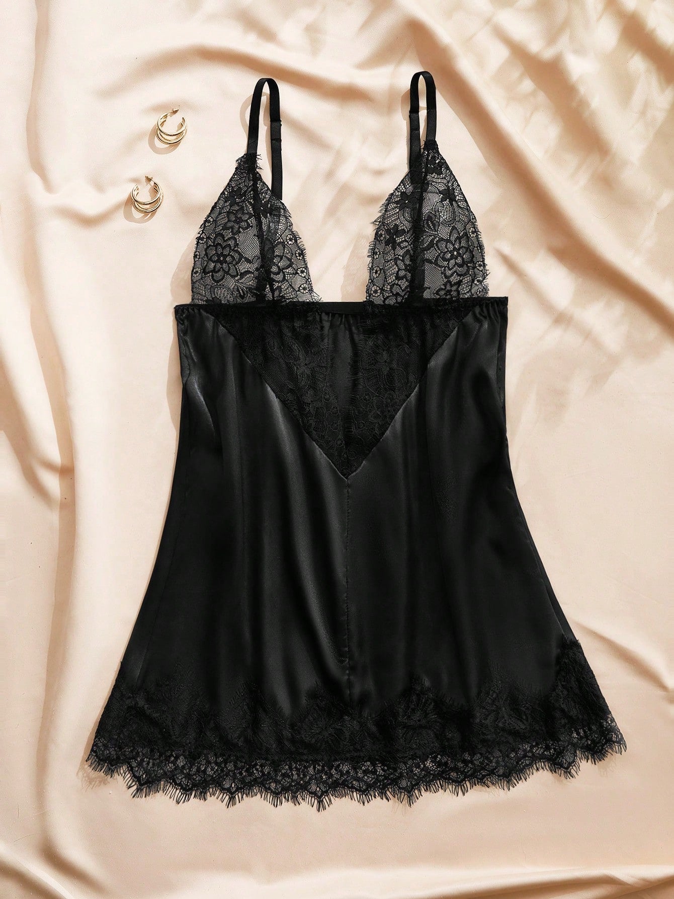 Black satin mini nightgown with contrast lace patchwork, deep V neckline, sleeveless design, and semi-sheer elegant finish