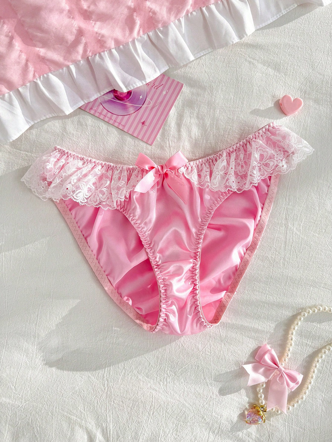 Women's pink low-rise triangle briefs with contrast lace, ruffle trim, bow detail, crisscross accents, and plant pattern