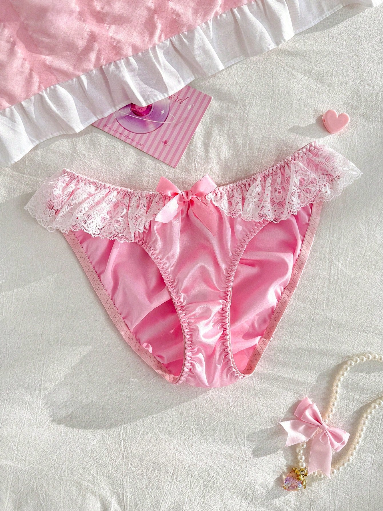 Women's pink low-rise triangle briefs with contrast lace, ruffle trim, bow detail, crisscross accents, and plant pattern