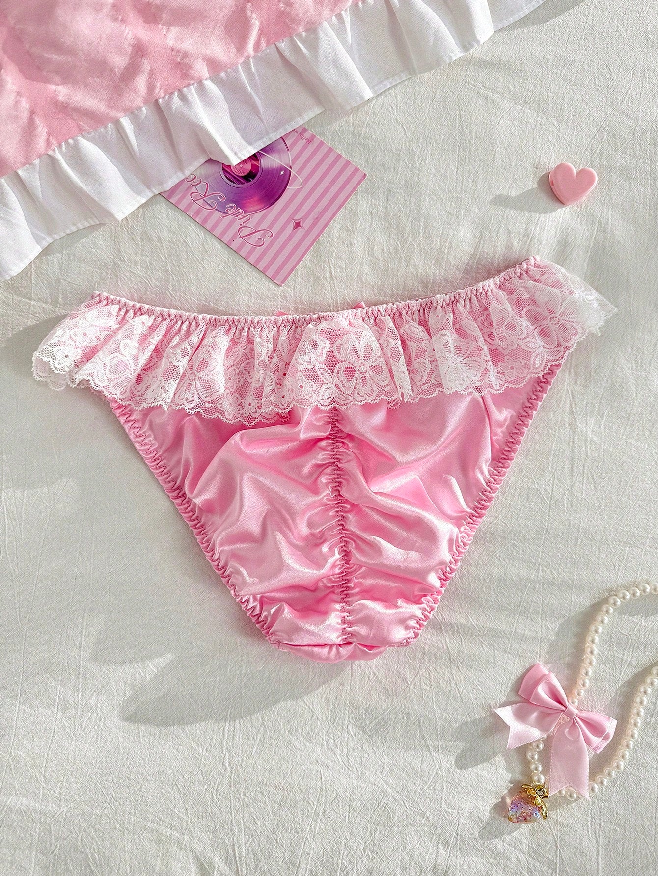 Women's pink low-rise triangle briefs with contrast lace, ruffle trim, bow detail, crisscross accents, and plant pattern