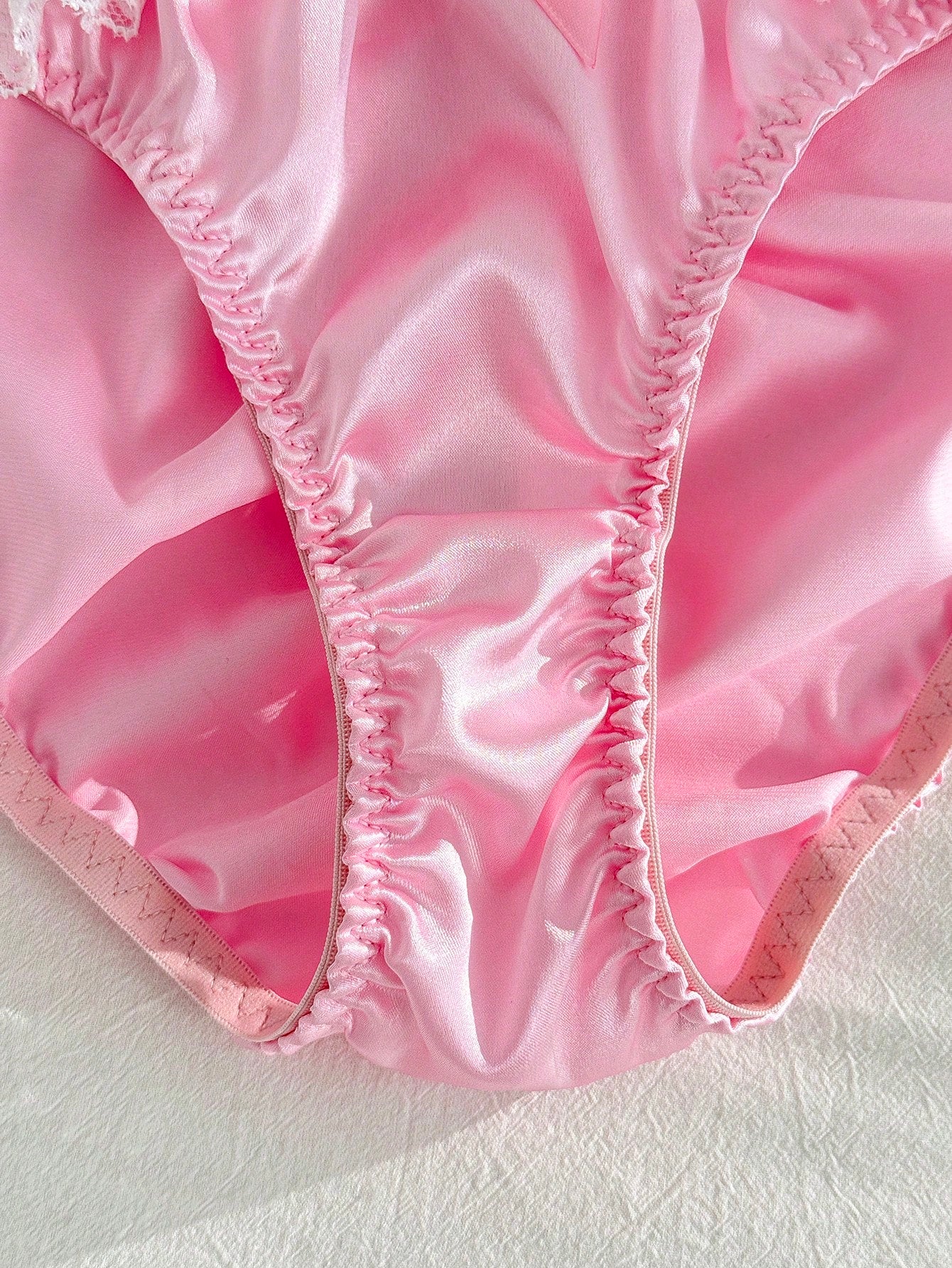 Women's pink low-rise triangle briefs with contrast lace, ruffle trim, bow detail, crisscross accents, and plant pattern