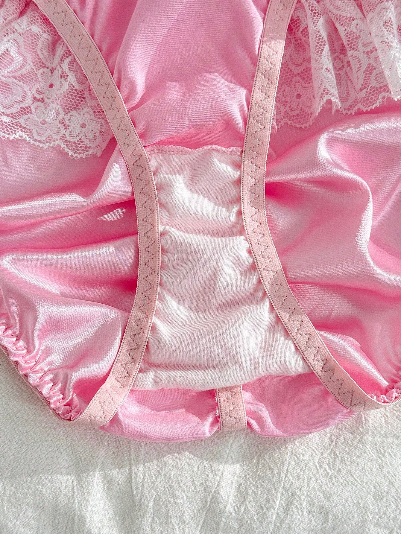 Women's pink low-rise triangle briefs with contrast lace, ruffle trim, bow detail, crisscross accents, and plant pattern