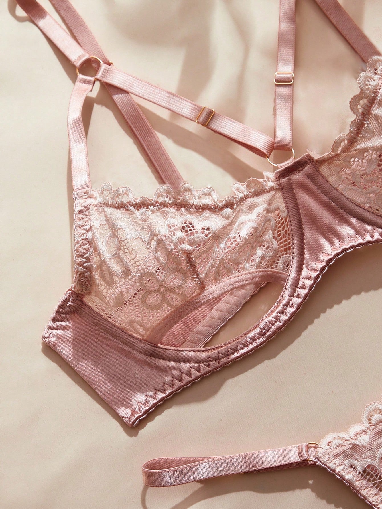 Pink French-style lingerie set featuring an underwire bra with adjustable straps and a low-rise thong with hollow-out detailing and plant pattern.