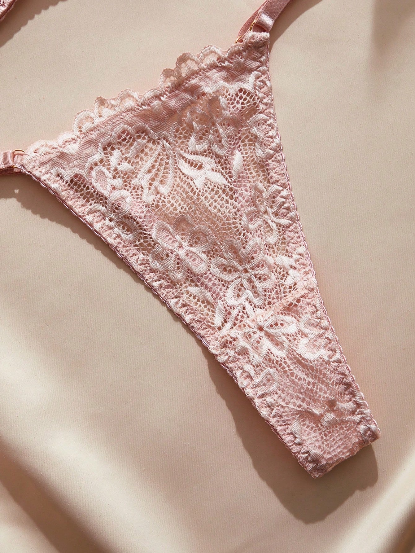 Pink French-style lingerie set featuring an underwire bra with adjustable straps and a low-rise thong with hollow-out detailing and plant pattern.