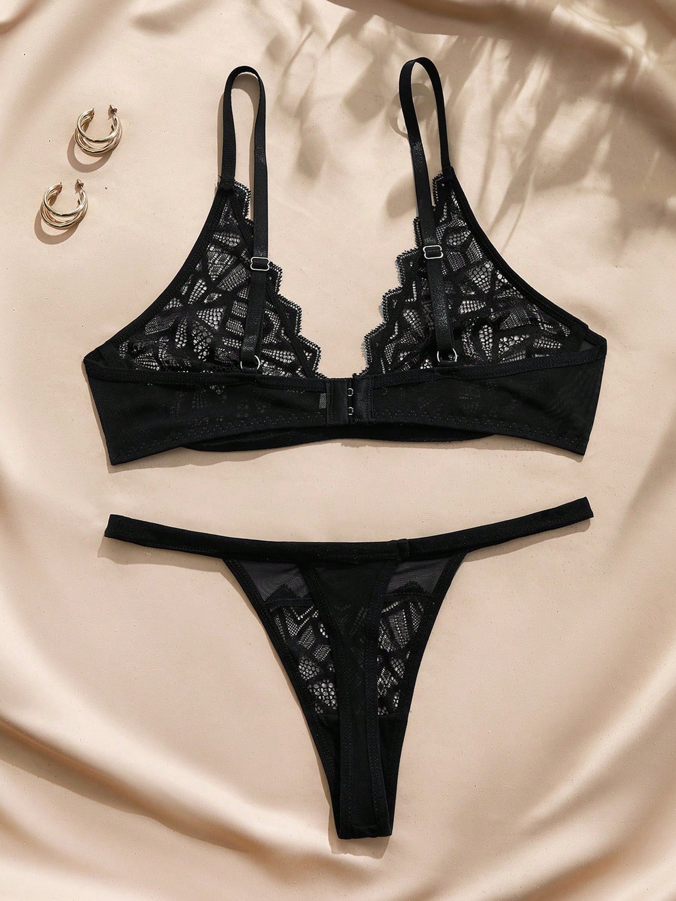 Black French romantic lace lingerie set with semi-sheer wireless bra, adjustable straps, bow detail, and matching mid-rise thong